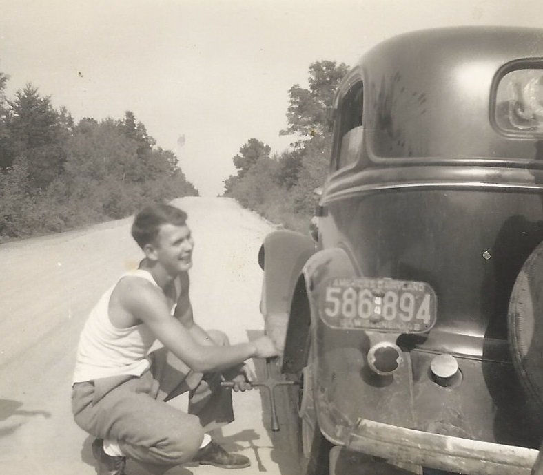 Hod Chrisinger changing a tire on a county road outside Taylor, Wis., in 1944.